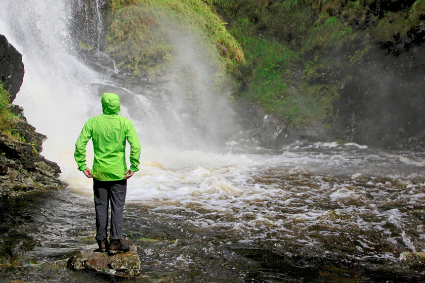 Man in green jacket in front of large cascade