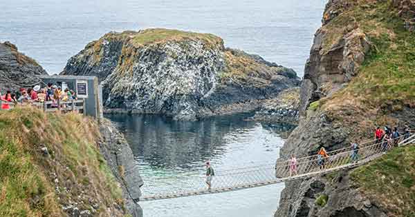 Narrow rope bridge across two rocks with the sea underneath