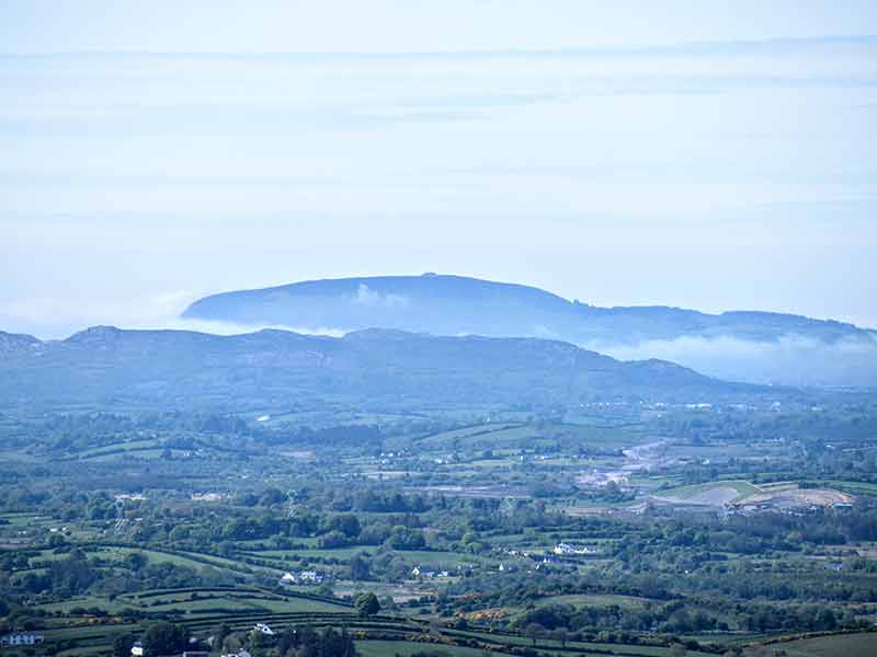 Blue silhouette of Knockanrea hill rising through the clouds