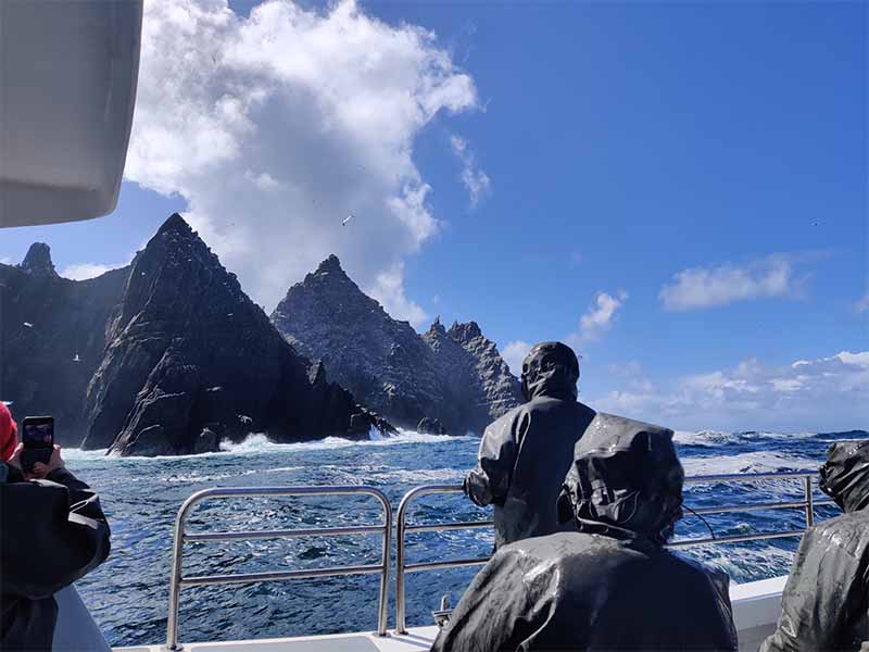 A few people on a boat looking at the Skellig Islands