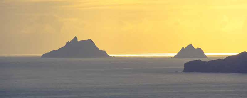 Golden sunset overlooking the rock pillars of Skellig Islands rising from the sea