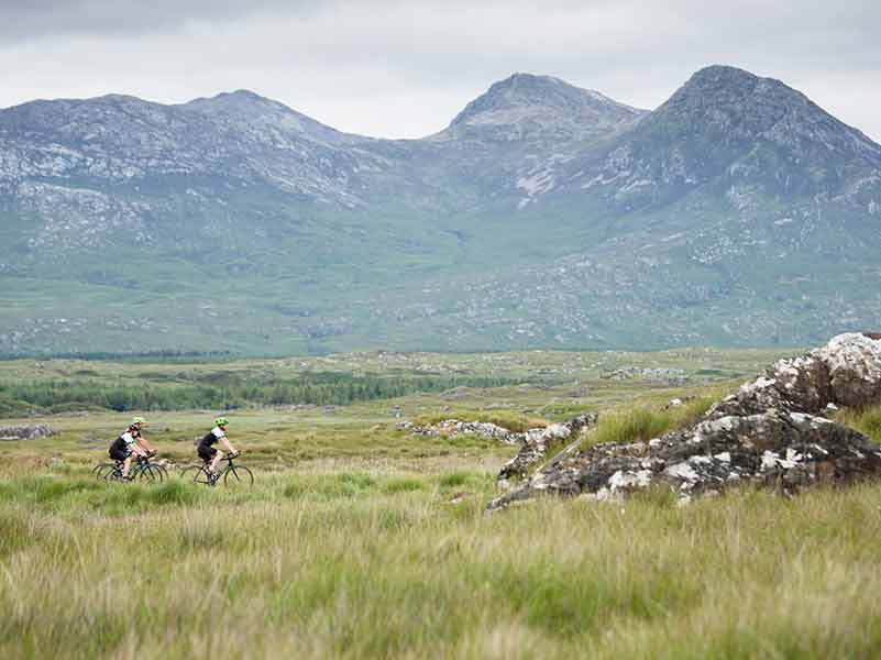 Cyclists in the distance under towering granite mountains.